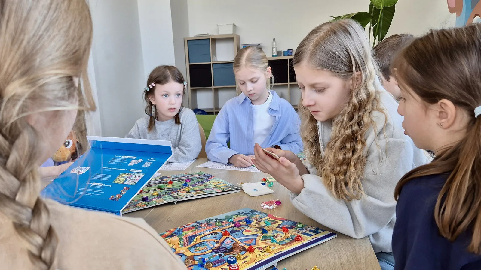 Dzieci skupione nad kolorową planszą Akademii Emocji